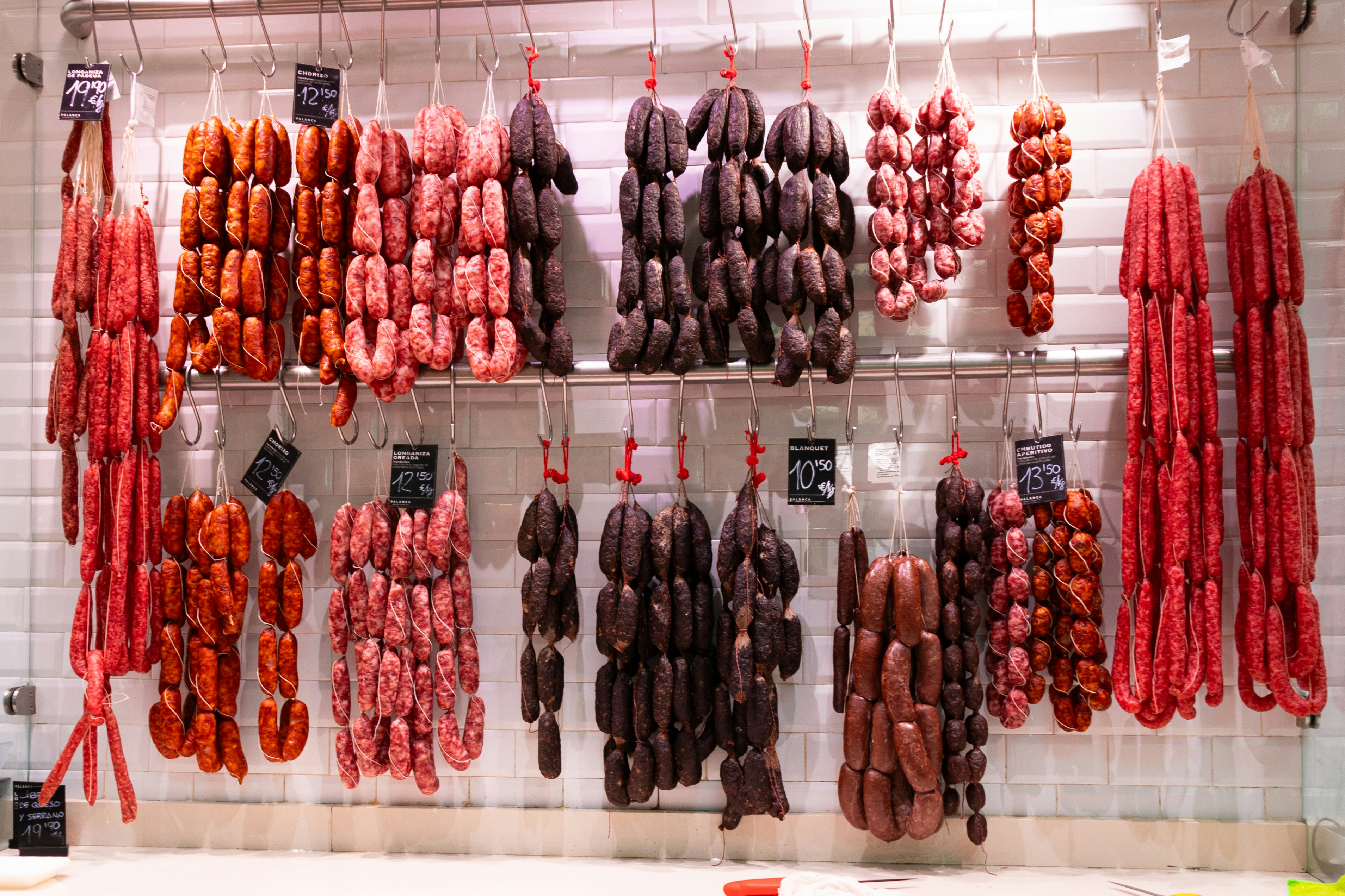 A bunch of sausage hanging from hooks in a kitchen photo Free Spain