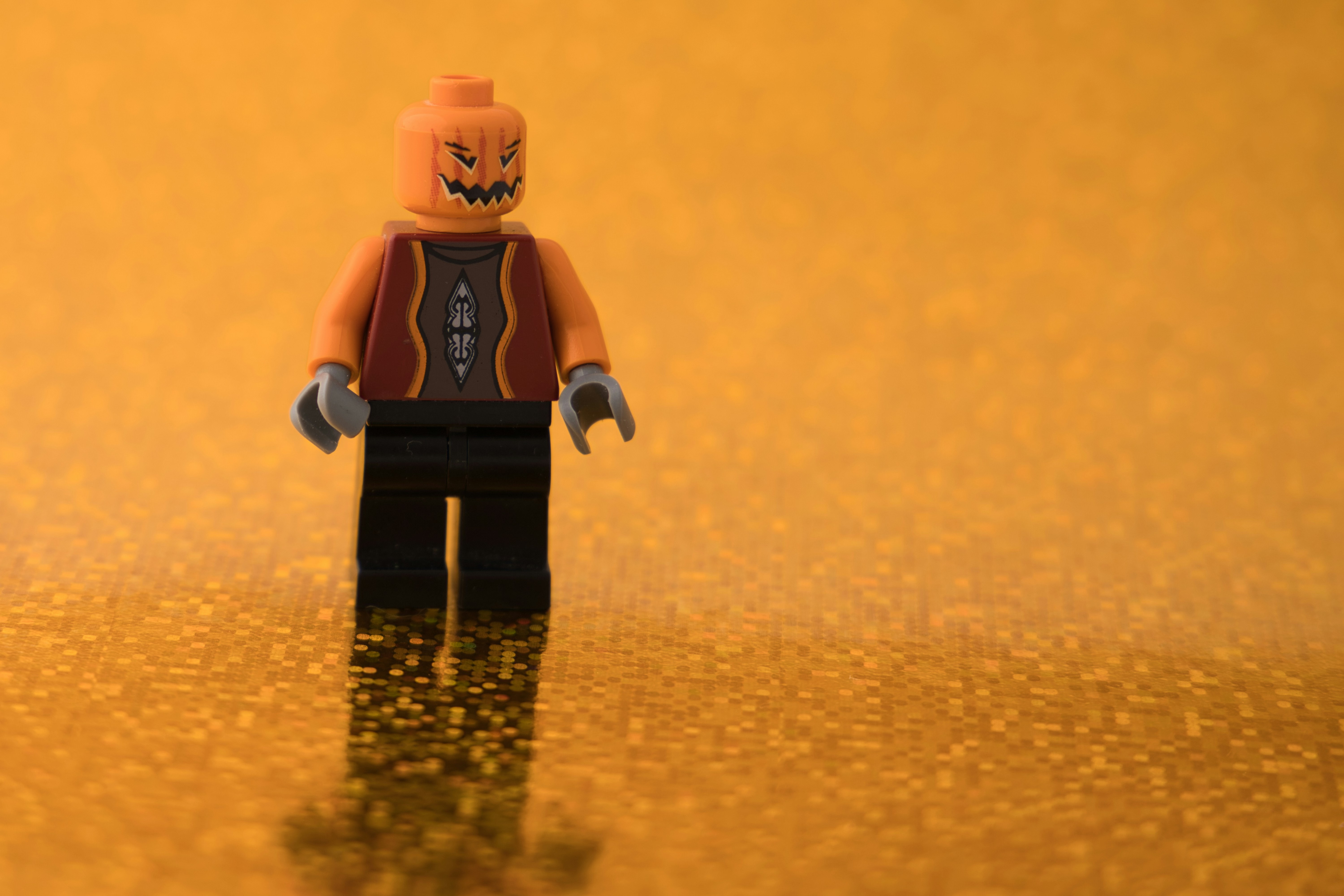 A lego figure is standing on a shiny surface photo Free Pumpkin head