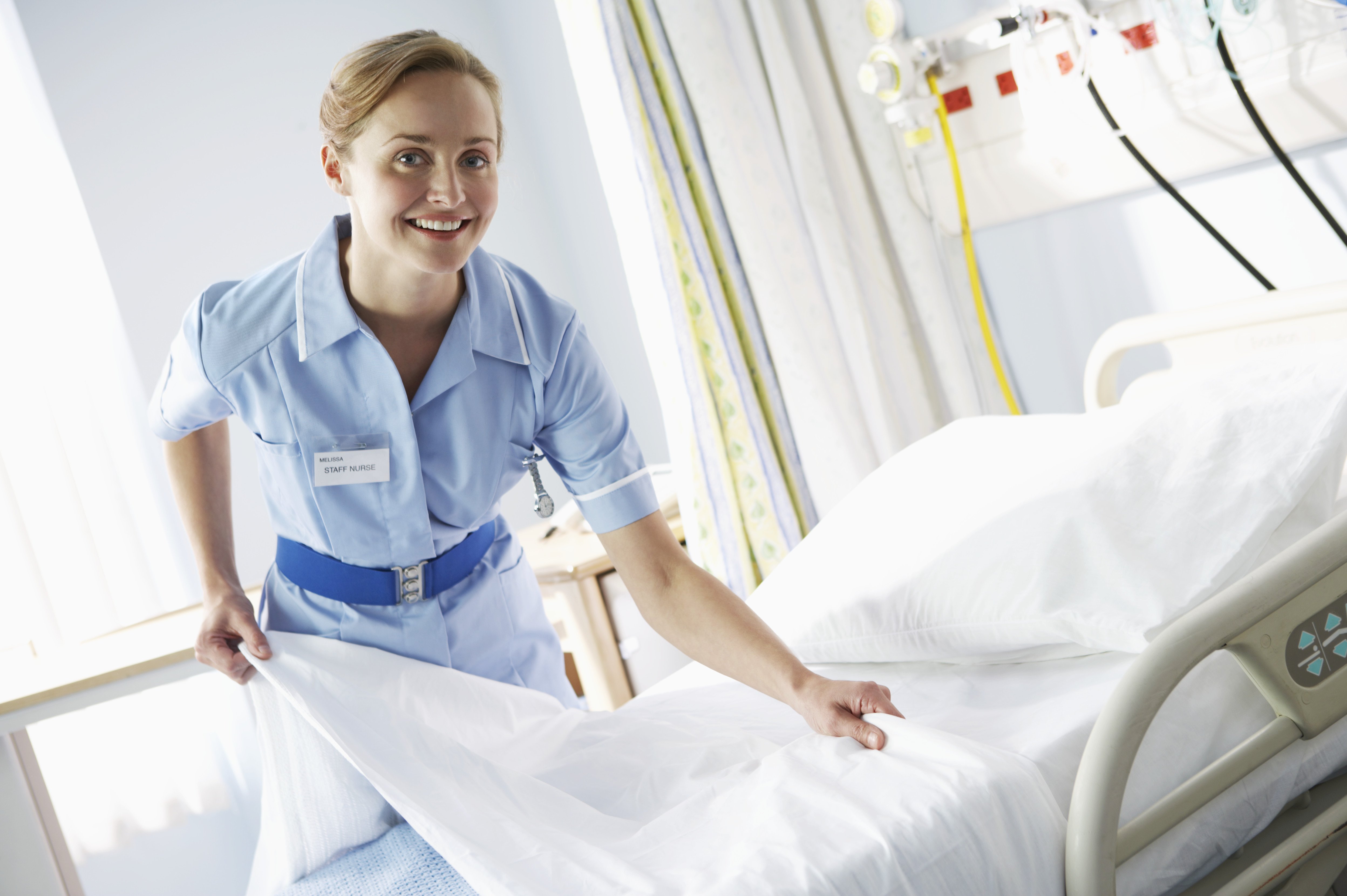 Portrait of a Female Nurse Making a Hospital Bed APIC