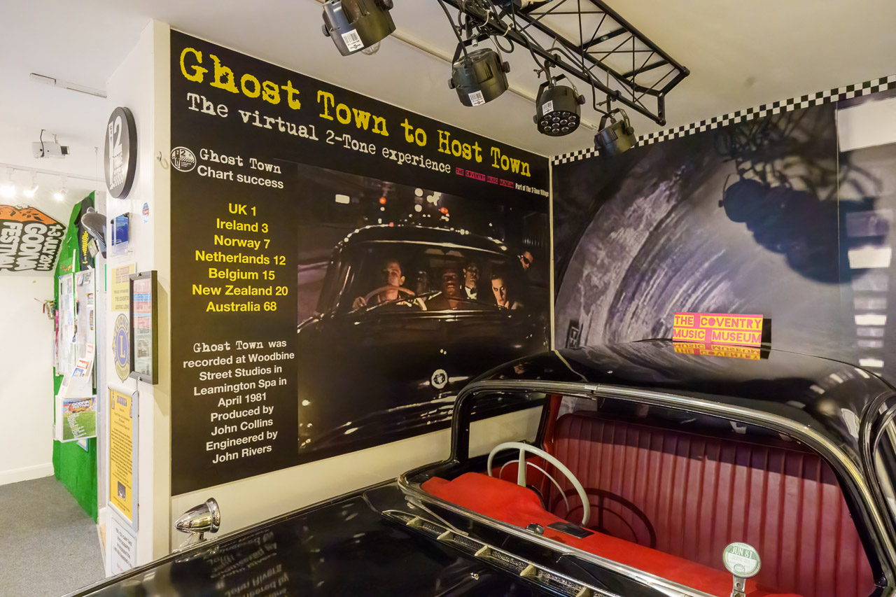 Inside the museum. There's a "Ghost Town to Host Town" poster for a virtual experience tour. Also in the picture is the car from the Ghost Town video.