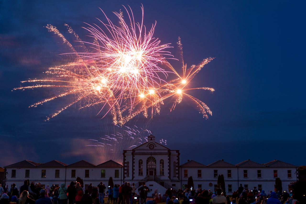 Fireworks light up the sky above Fort Mitchel on Spike Island. a crowd watches, surrounded by the buildings of the fort