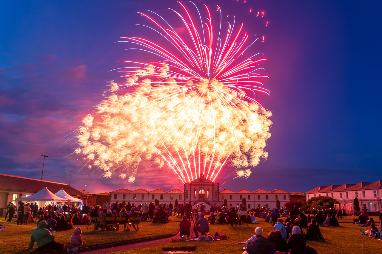 Fireworks light up the sky above Fort Mitchel on Spike Island. a crowd watches, surrounded by the buildings of the fort