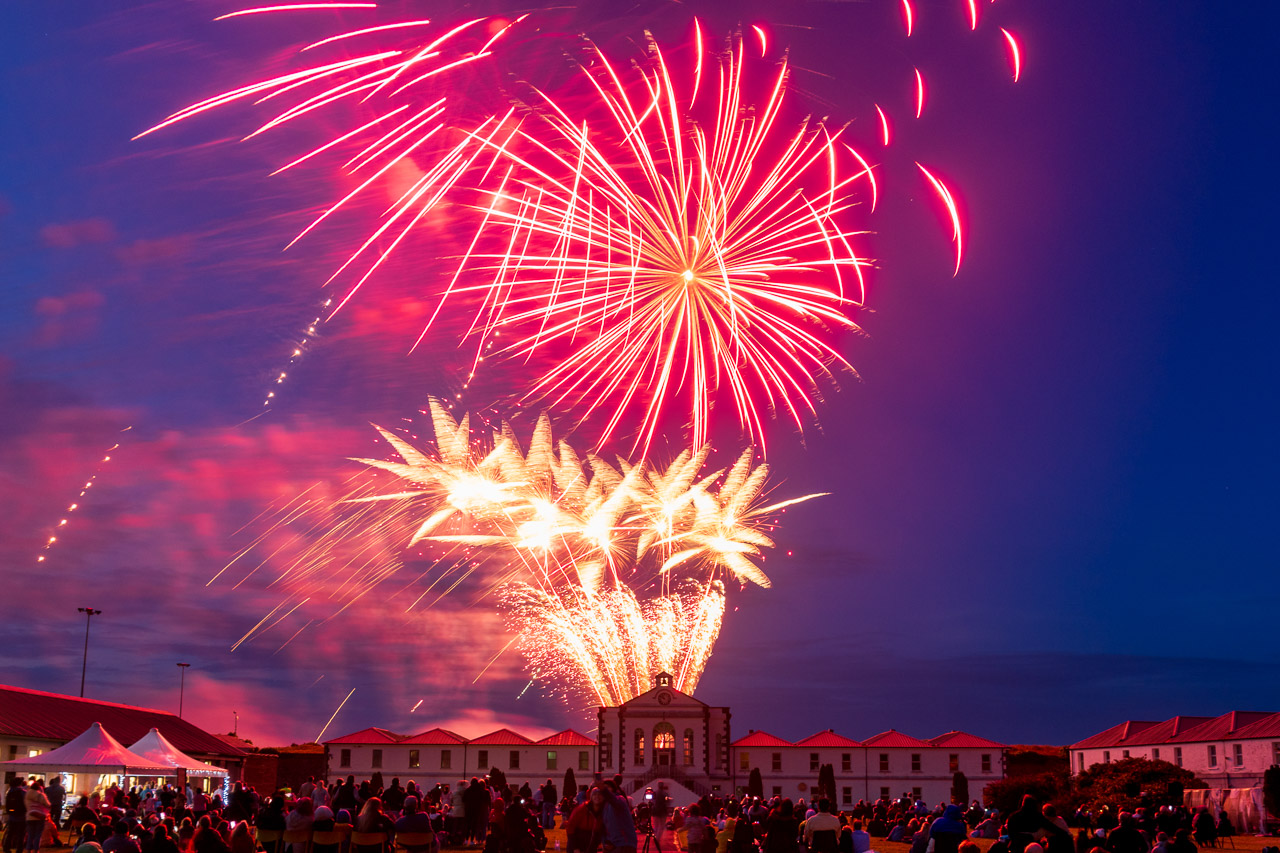 Fireworks light up the sky above Fort Mitchel on Spike Island. a crowd watches, surrounded by the buildings of the fort