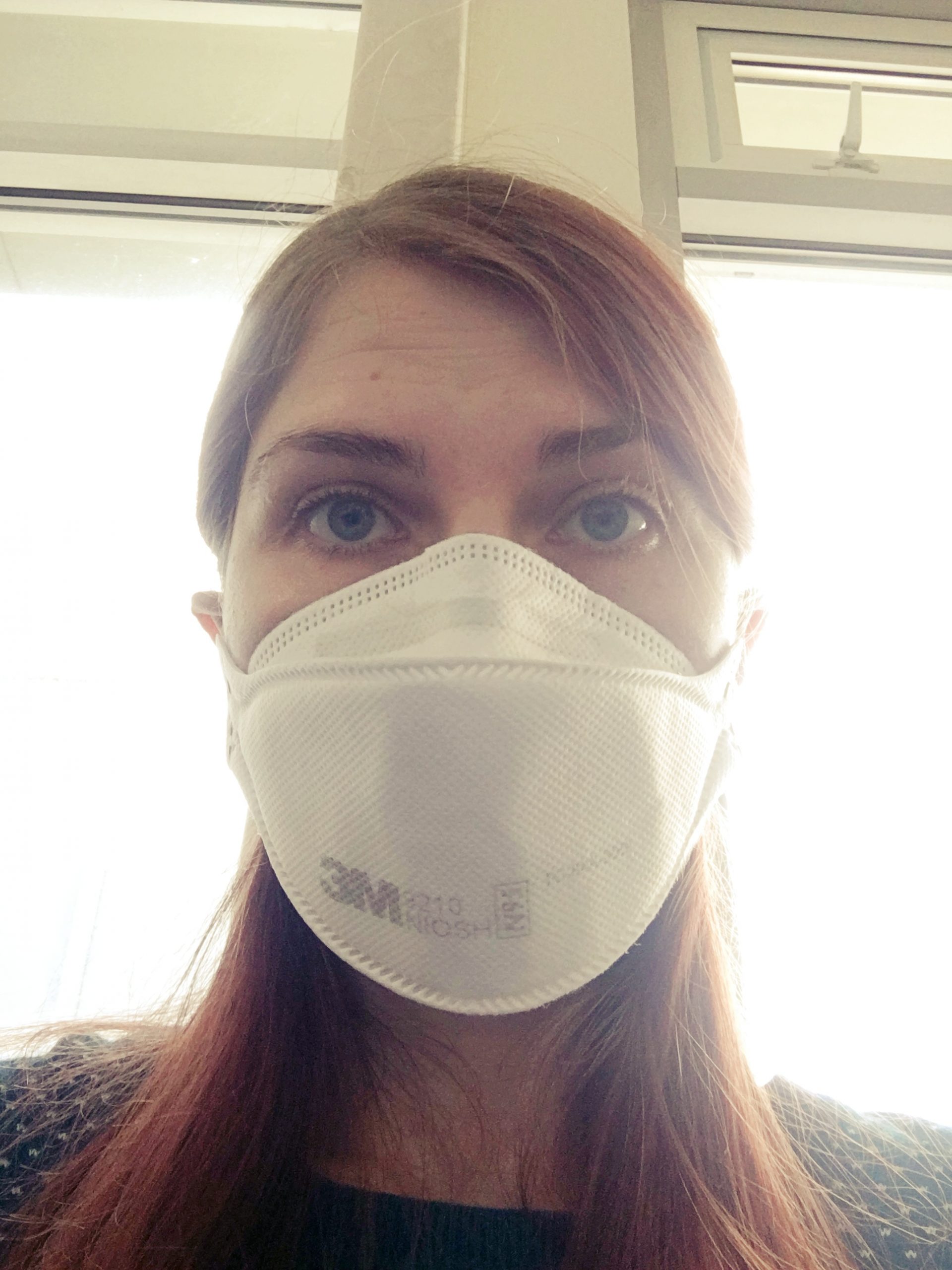 A head/shoulders photo of me in my mask waiting in the hospital, with the light from the window behind me.