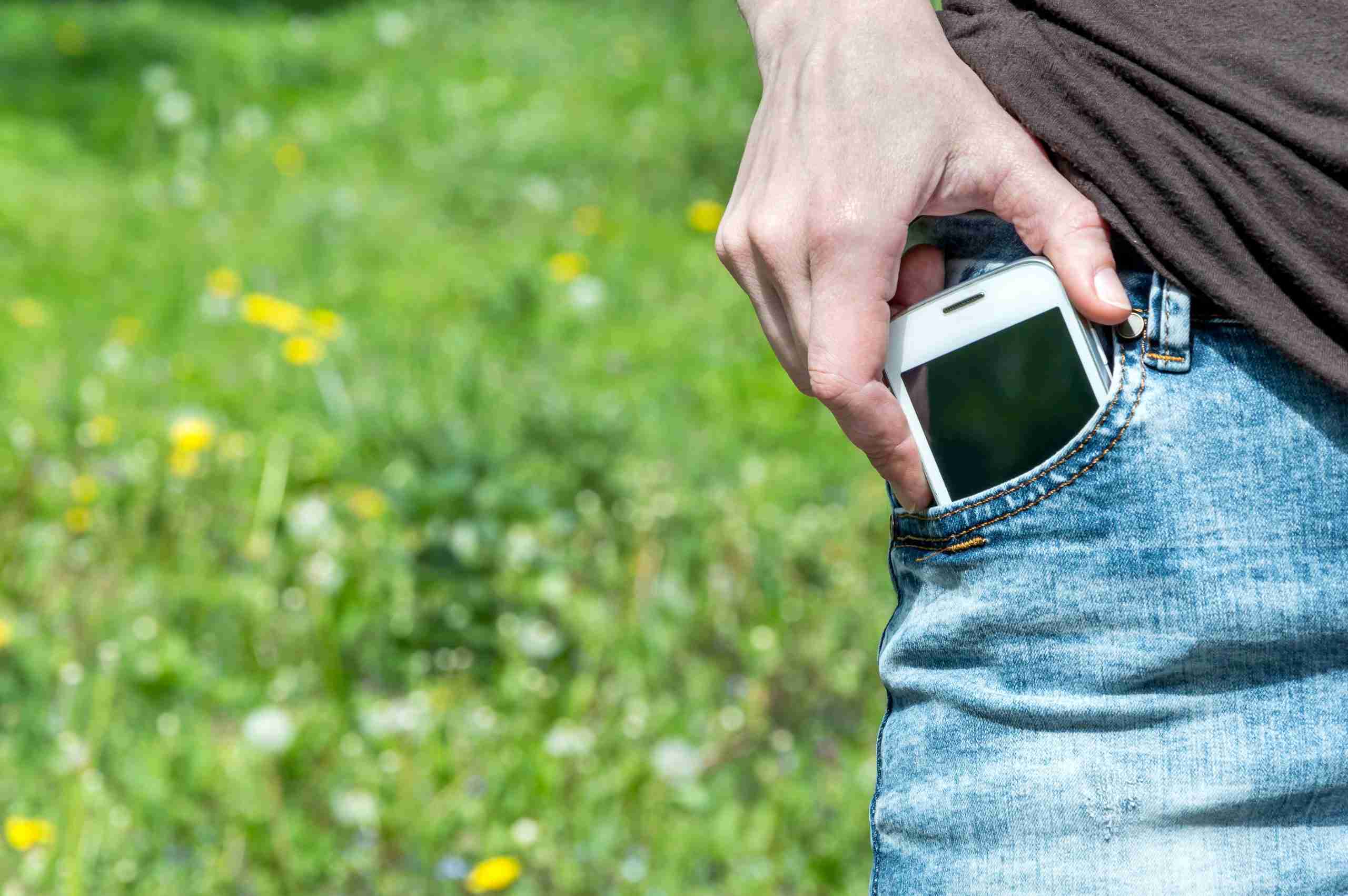 Person pulling a smartphone from their jeans pocket Iowa Compass