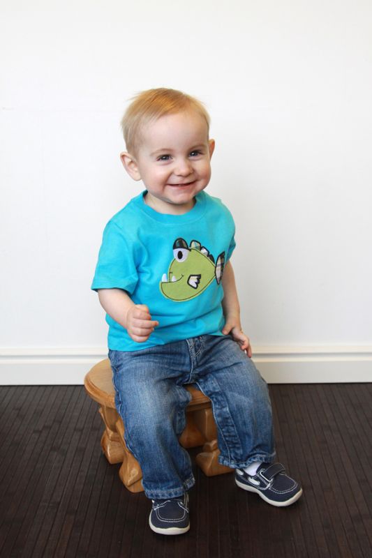 A little boy on a stool in front of a white wall
