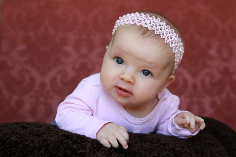 A baby girl in front of a pink fabric background