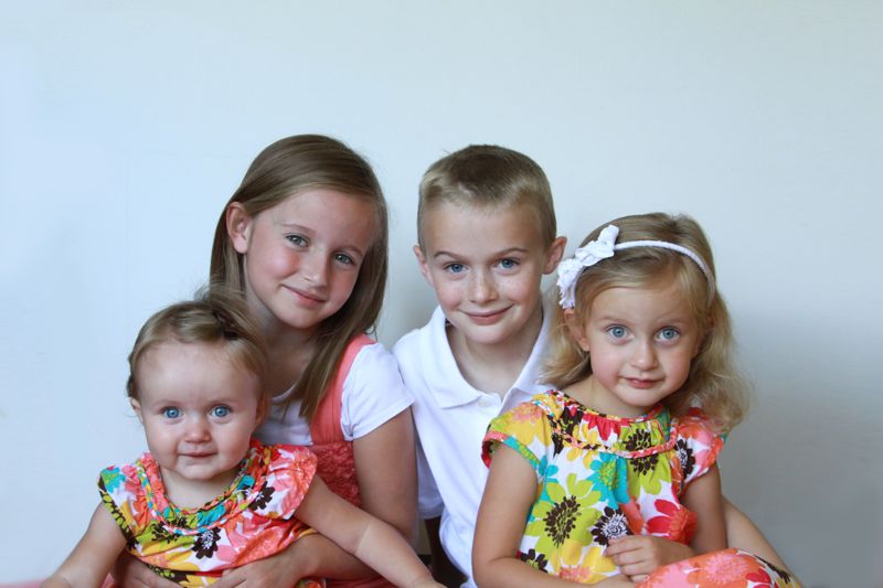 four siblings posing together in front of a white background