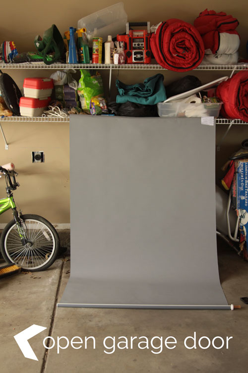 A grey window shade hanging from a shelf in a garage