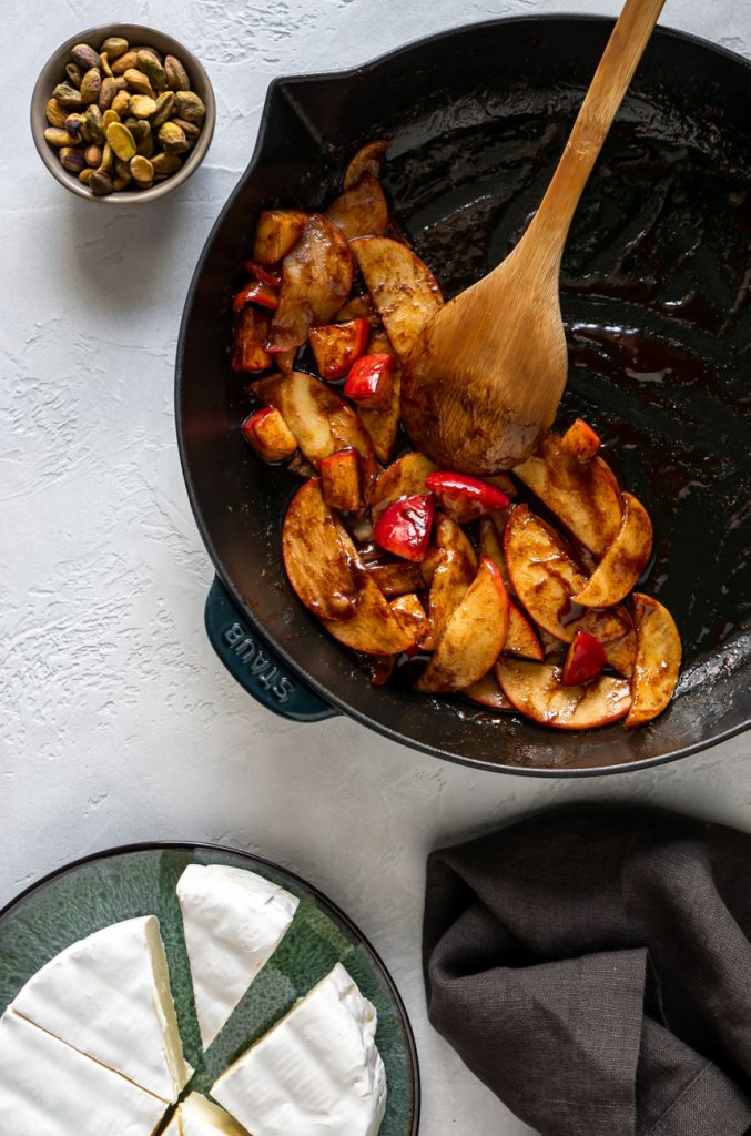 cinnamon glazed apples in a skillet with a wooden spoon