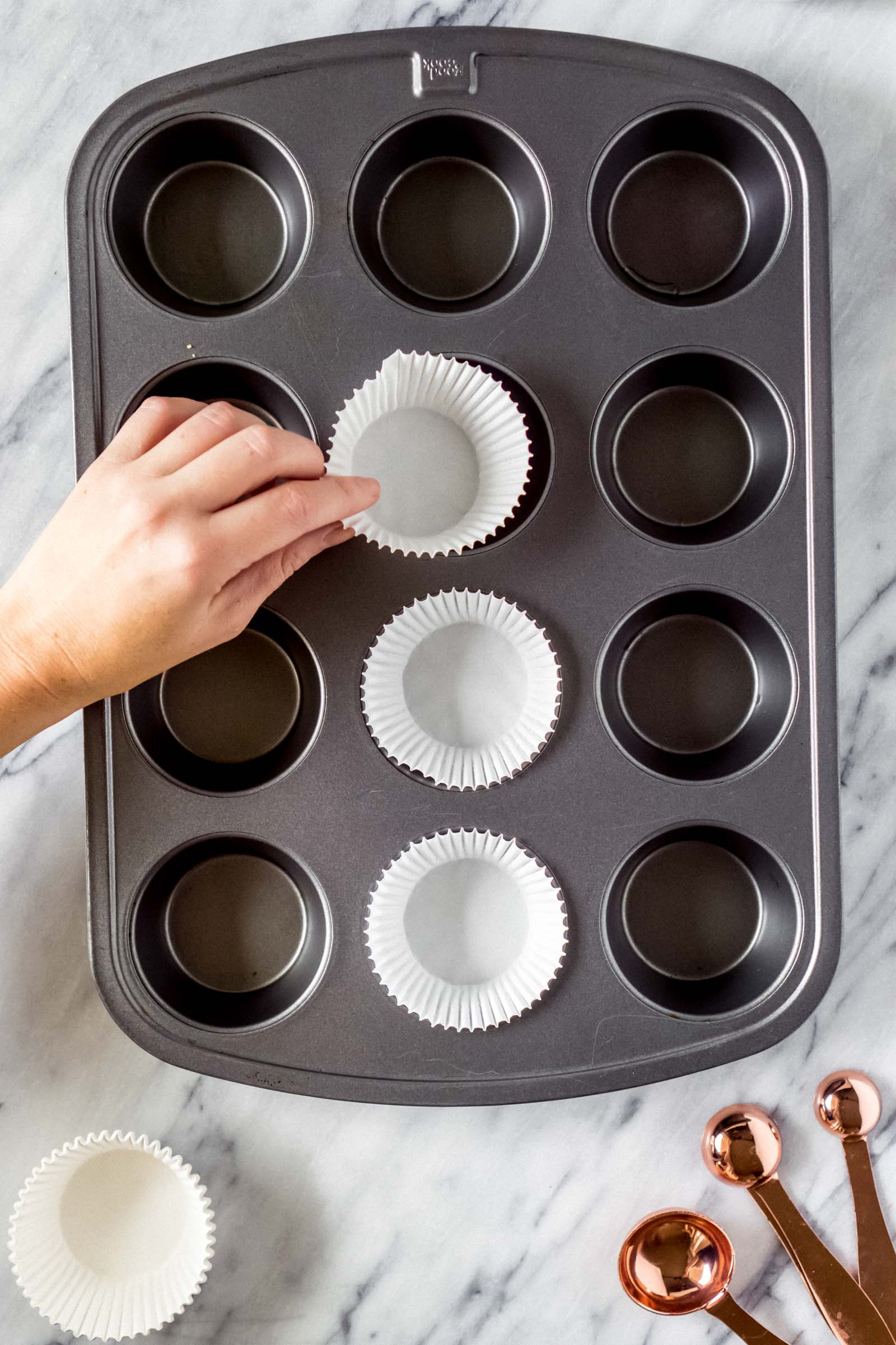 a hand placing muffin wrappers in a muffin tin