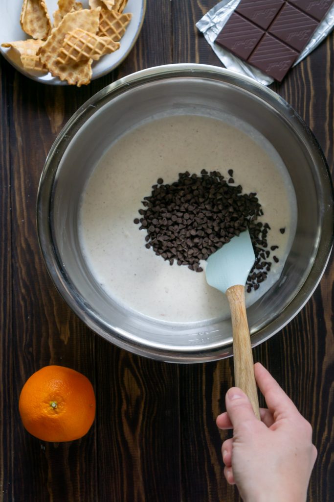 spatula mixing chocolate chips into cannoli dip