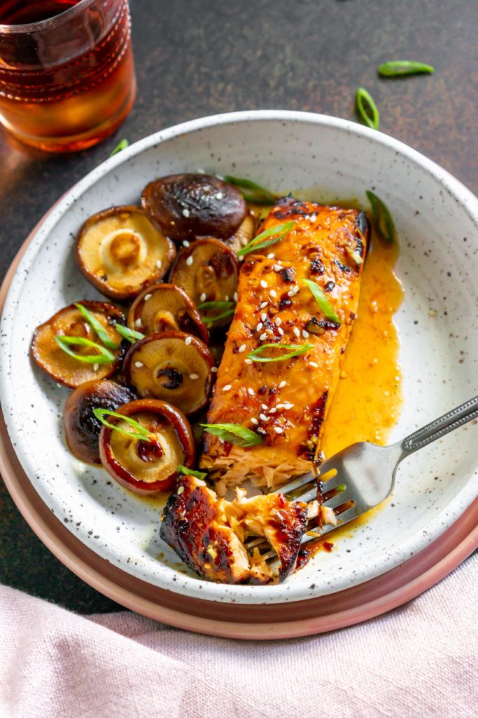 silver fork on a white plate with asian salmon and mushrooms
