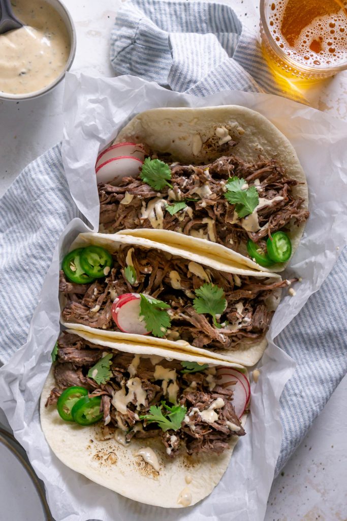 barbacoa tacos with a blue napkin and crema