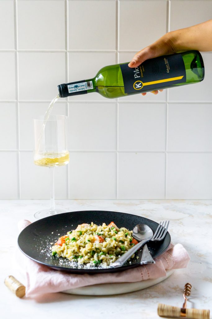 pouring wine into a glass next to a plate of food