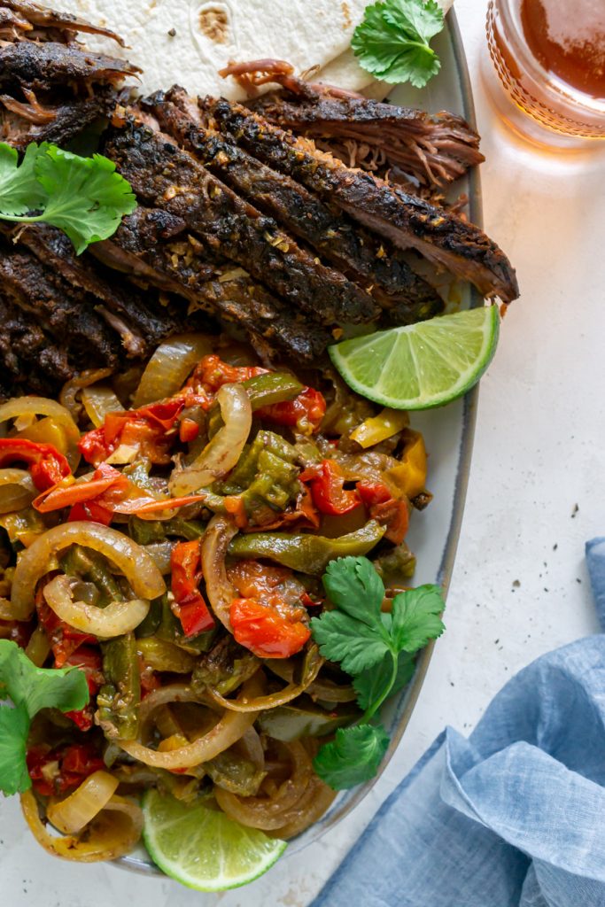 steak fajitas on a serving plate with lime wedges