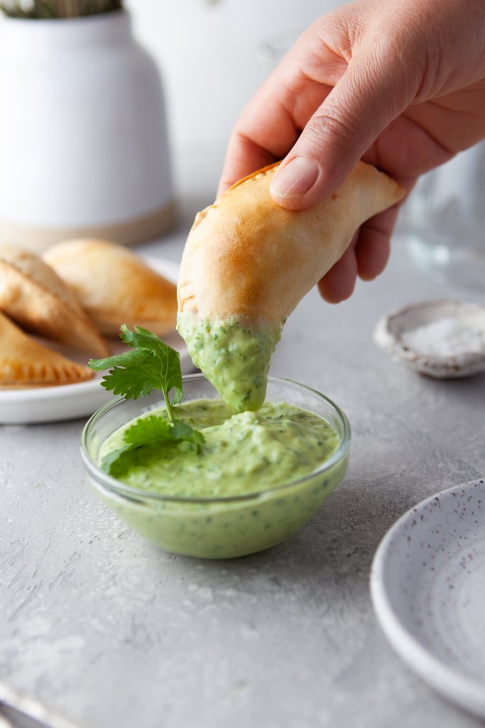 dipping an empanada in sauce