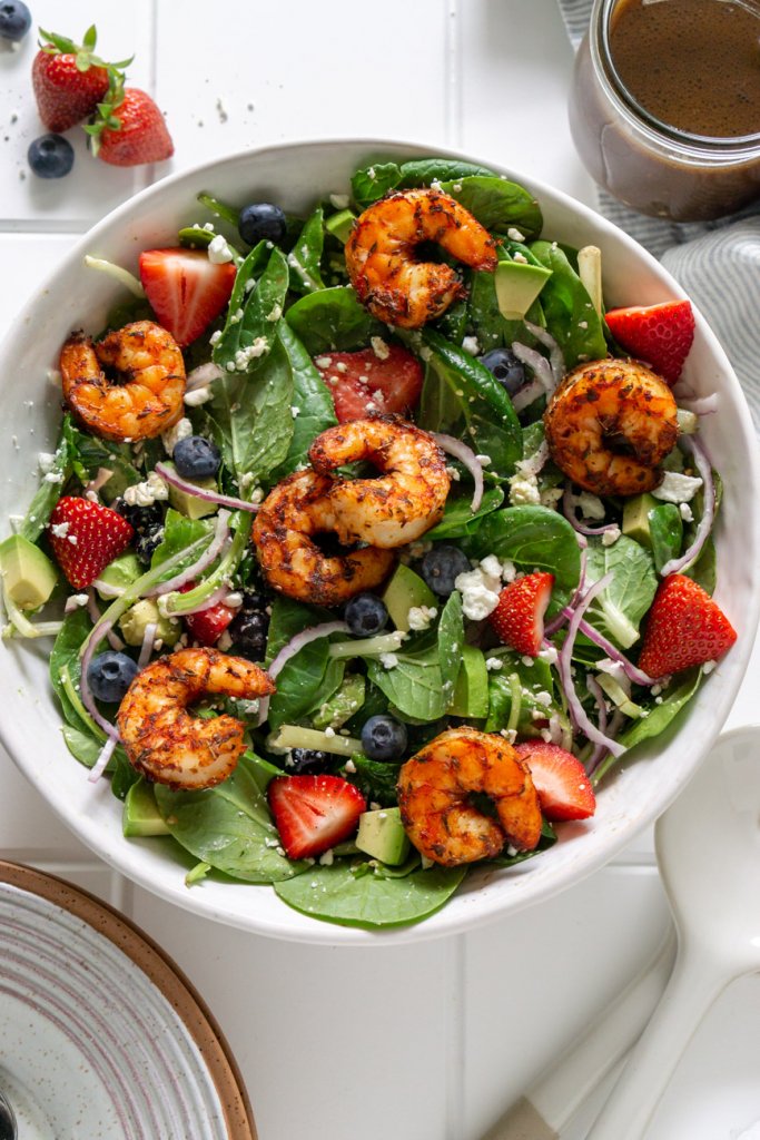 strawberry spinach salad with shrimp in a white bowl