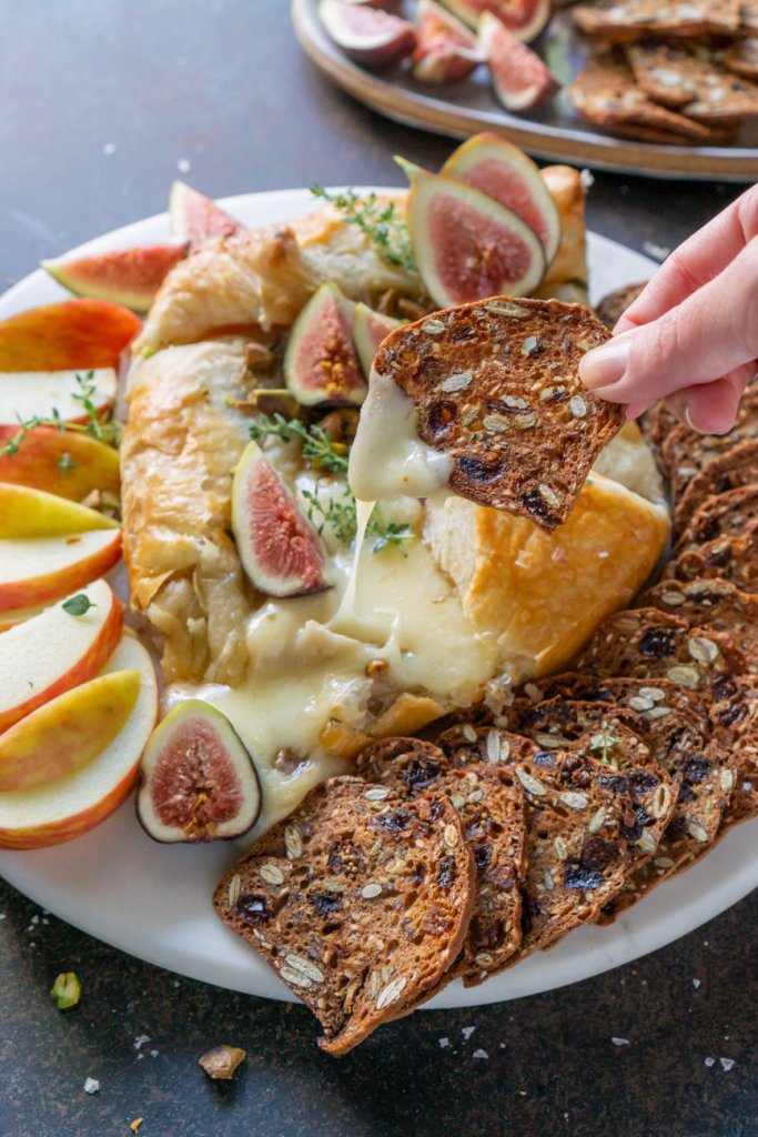 dipping a cracker in melted brie