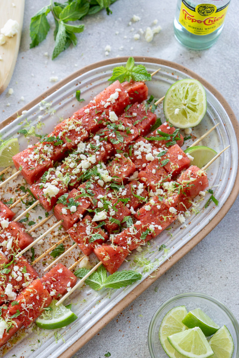 Watermelon skewers on a serving plate with lime.