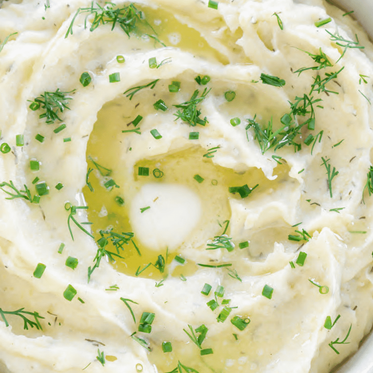 Slow cooker mashed potatoes garnished with dill and green onions.