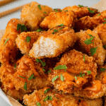 Bang bang chicken on a plate, one piece with a bite taken.