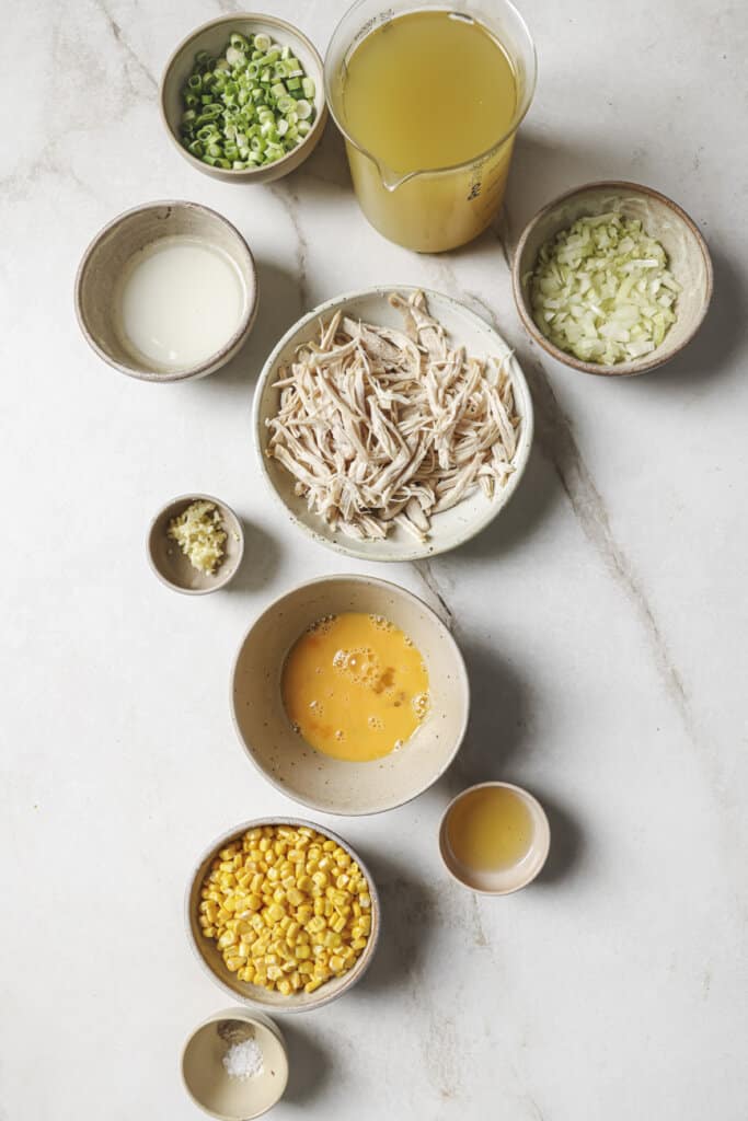 shredded chicken, corn, egg, chicken broth, and green onion in small ingredient bowls