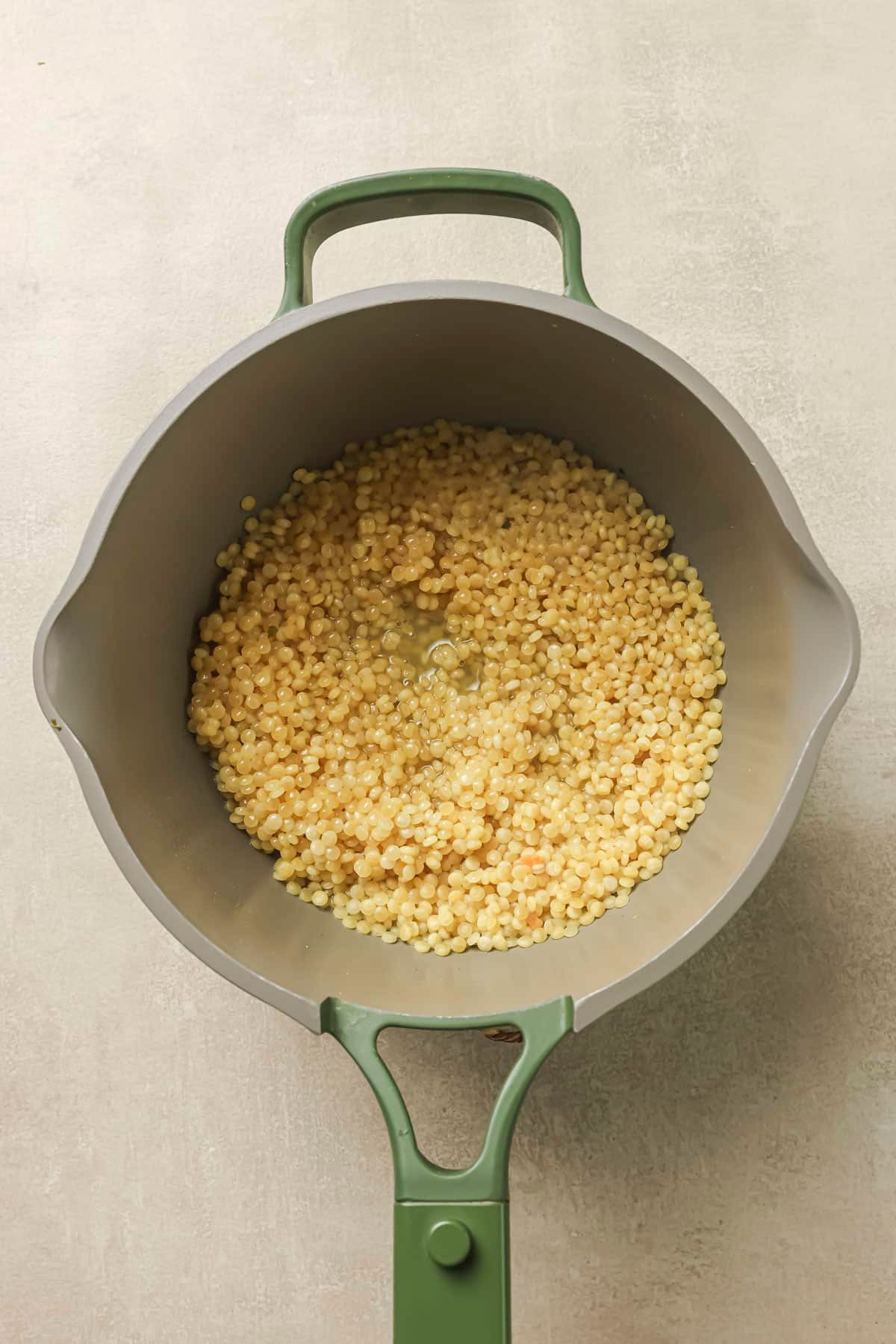 Cooking couscous in chicken broth in a large pot.
