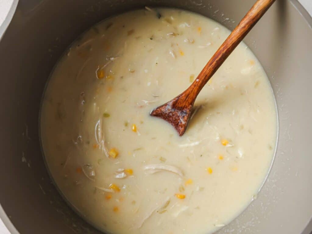 Whisked egg being poured into the soup while stirring to create delicate egg ribbons.