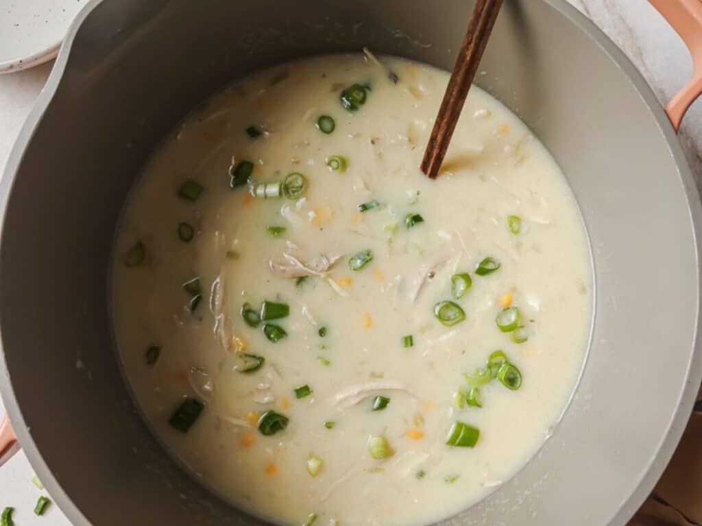 Bowls of creamy chicken corn soup garnished with fresh sliced green onions.