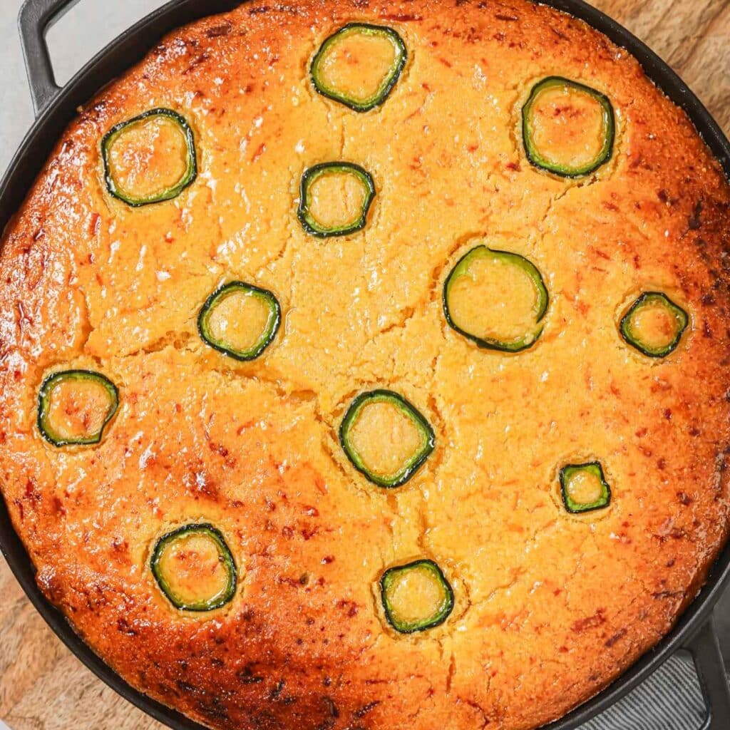 An overhead shot of cornbread chicken pot pie with cheddar and jalapenos baked in a pie dish.