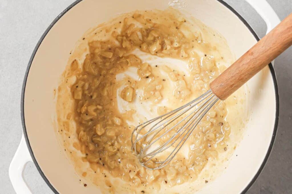 Whisking flour into a pan to make a roux.