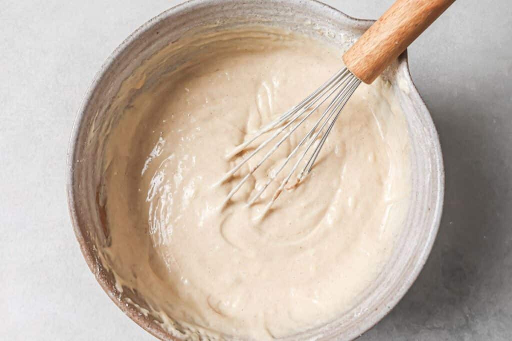 Pancake mix prepared in a mixing bowl with a whisk resting on the side. 