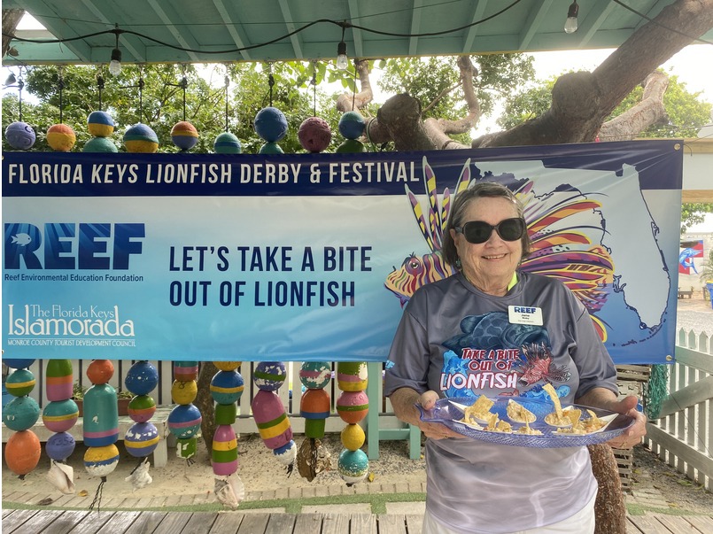 a woman holding a plate of food in front of a sign