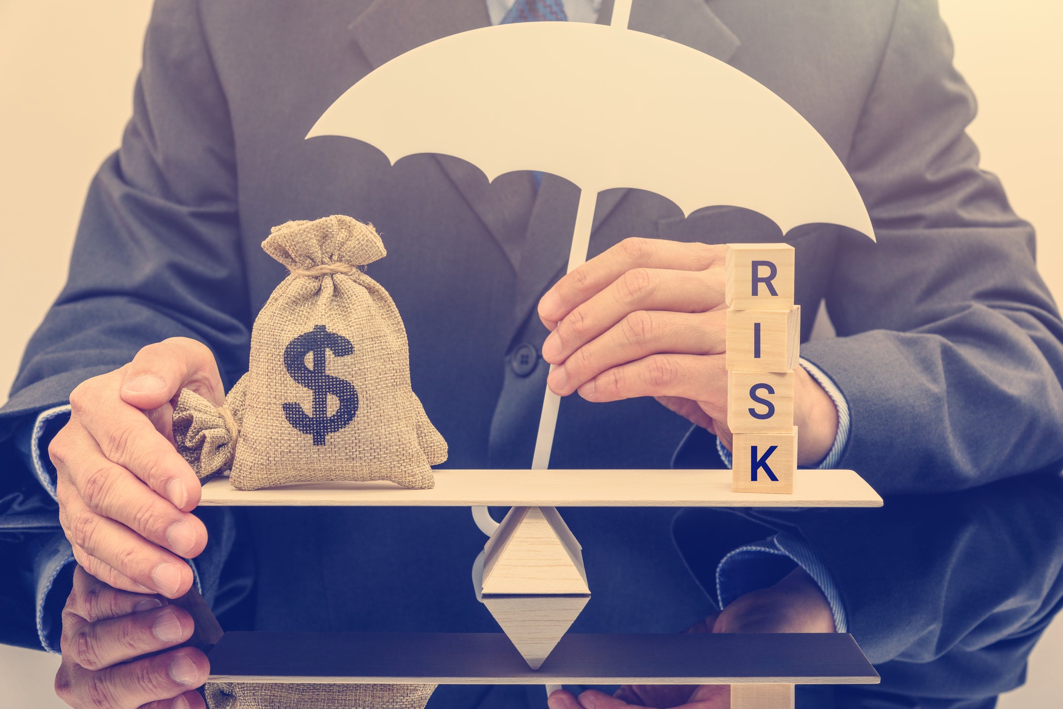 19_06_05-a-man-with-the-word-risk-and-a-bag-of-money-balanced-in-front-of-him-on-a-simple-balance-with-an-umbrella-over-the-whole-_gettyimages-1058471606.jpg