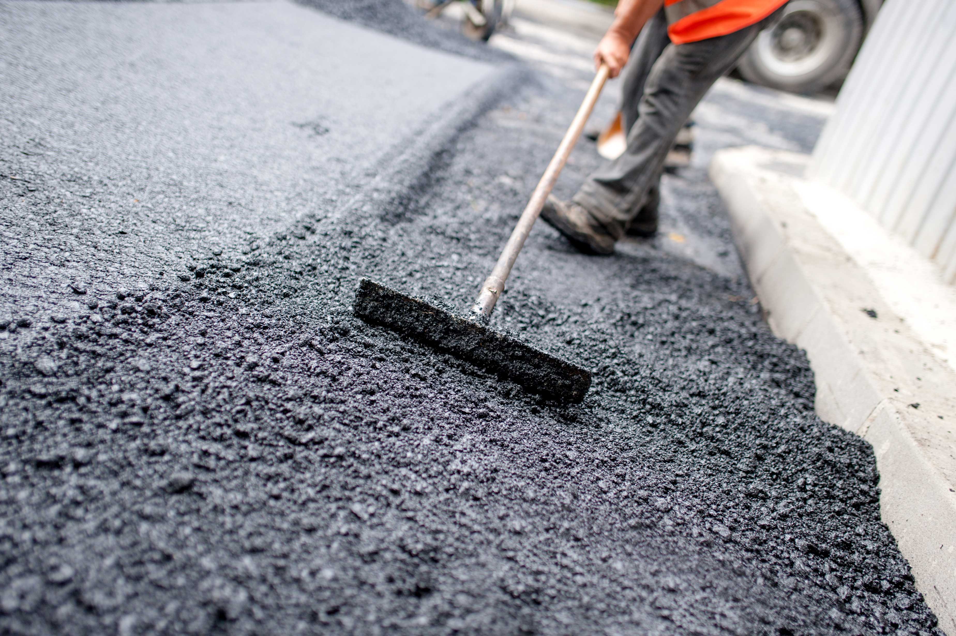 Worker levelling fresh asphalt on a road construction site Lakeview