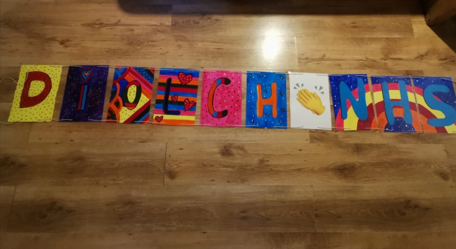 This is a banner made by a 12 year old, each letter has a different coloured background, and it spells out Diolch NHS