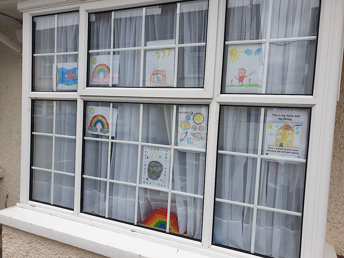 A window with many small panes showing colourful drawing by children