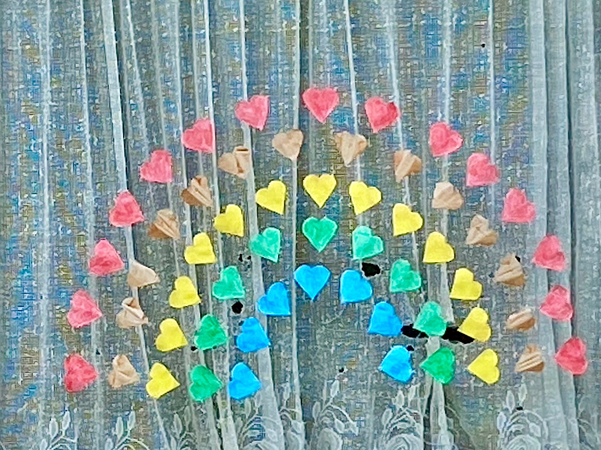 A window with a rainbow made out of coloured heart shapes