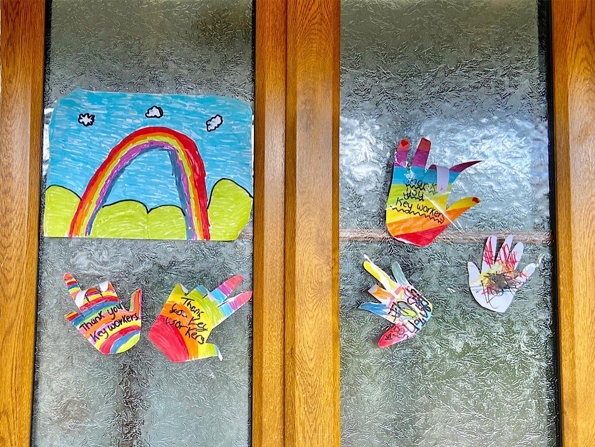 A window with a rainbow painting and several multi-coloured hand shapes