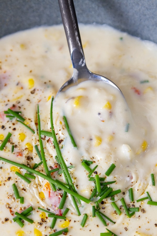 a spoon lifting thick creamy chowder out of a bowl of soup.