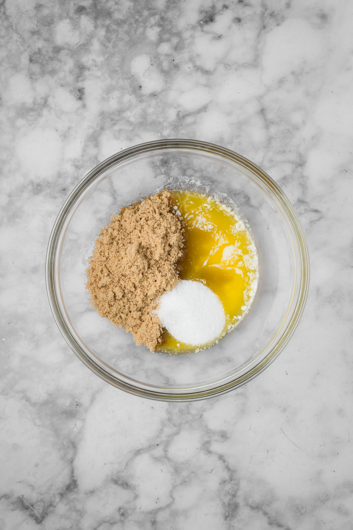 Melted butter, brown sugar, and white sugar in a glass bowl.