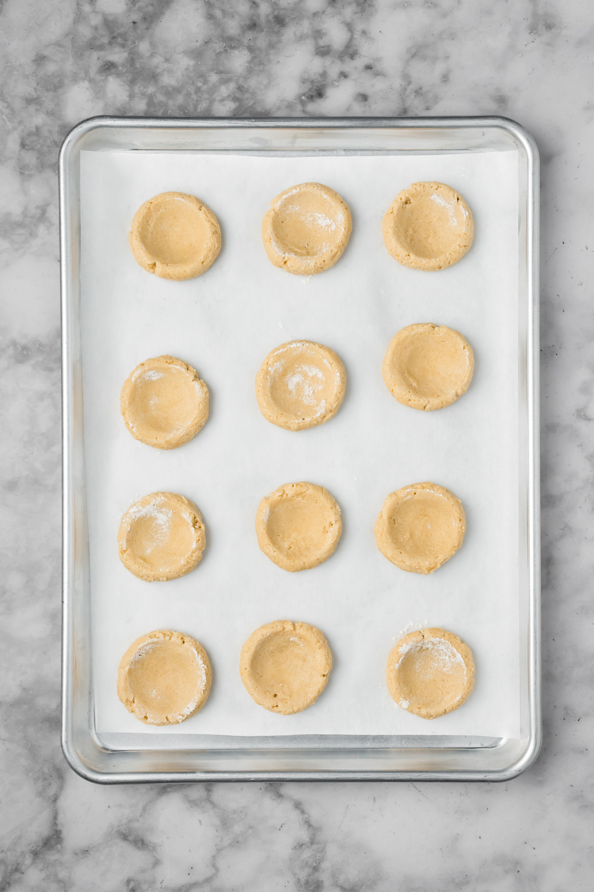 Cookie dough balls with the Tbsp indention on a baking sheet.