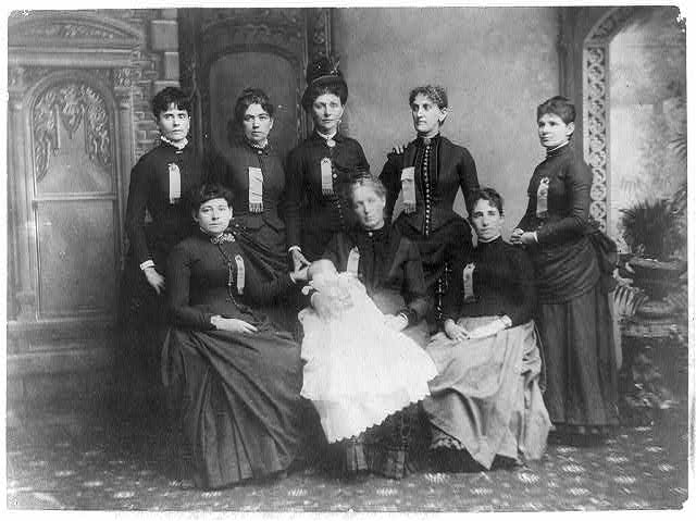 Black and white photo of women form the late 1800's. One woman holding baby in christening gown