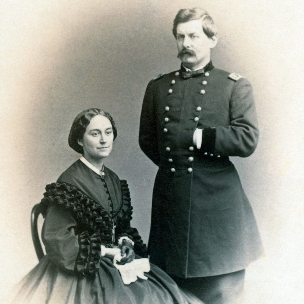 black and white carte de visite with seated woman and standing man in 1860's military uniform. Woman in hoop skirt