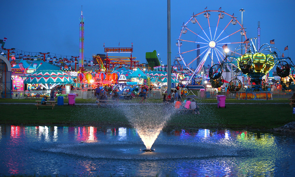 NYS FAIR Rides are reflected in the NY Experience pond at … Flickr