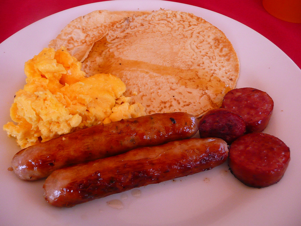 Leftover pancakes with maple syrup, sausage, scrambled eggs a photo