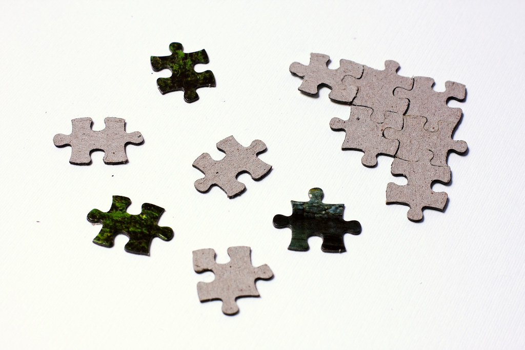 Scattered puzzle pieces next to solved fragment Several ji… Flickr