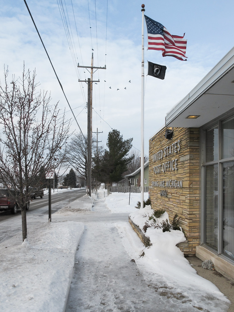 Airborne pigeons at a post office with a sidewalk. Flickr