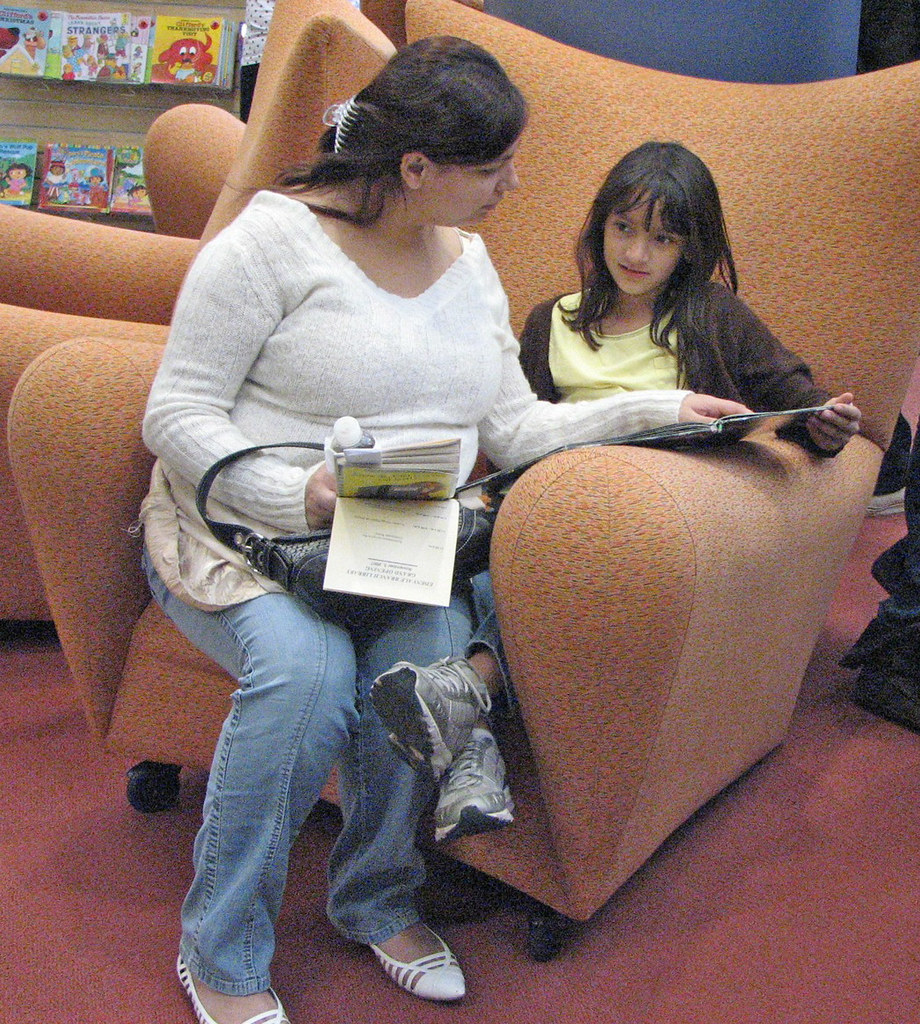 woman and girl reading on comfy chair San José Public Library Flickr